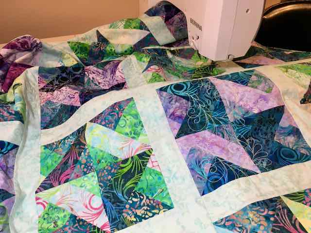 Beautiful machine quilted designs on a "Jelly Roll" pieced strip quilt with a a two piece flange binding.